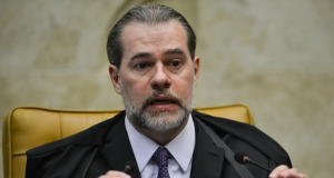 Dias Toffoli de terno e gravata, falando em microfone com expressão desconfiada