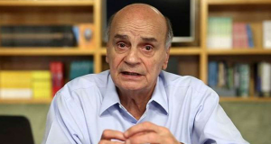 Dráuzio Varella de camisa social azul clara, falando e gesticulando para a câmera