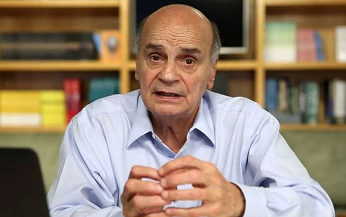 Dráuzio Varella de camisa social azul clara, falando e gesticulando para a câmera