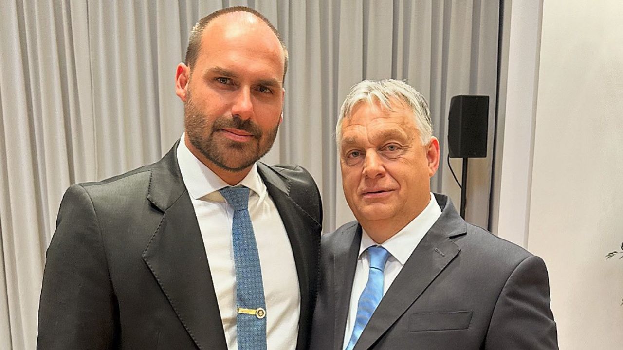 Eduardo Bolsonaro e o Primeiro-Ministro da Hungria, Viktor Orbán posando para foto lado a lado, ambos sem sorrir