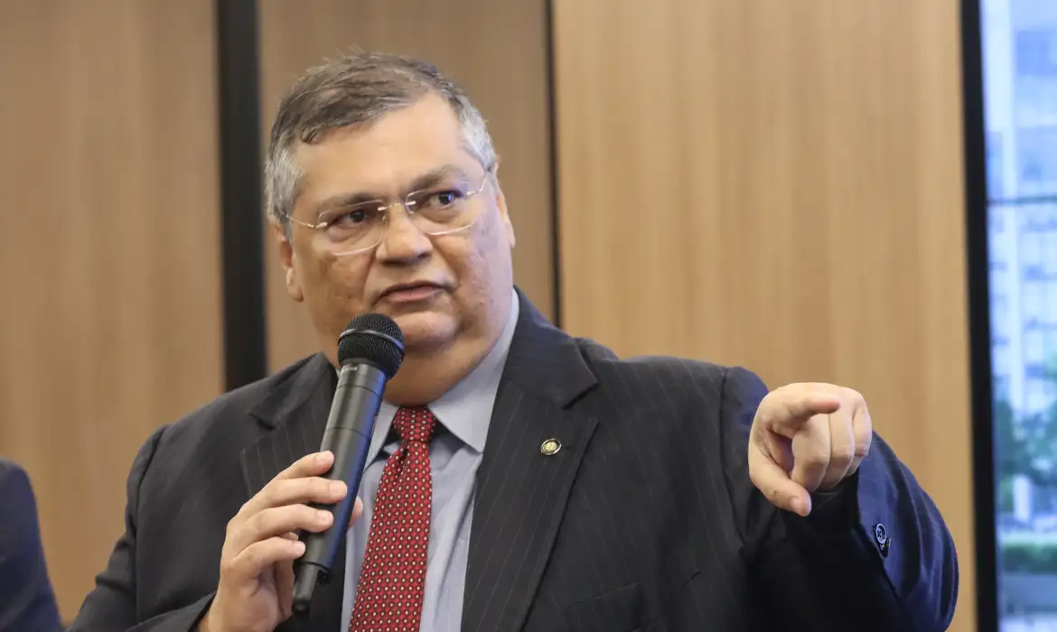 Flávio Dino de óculos, falando, olhando para o lado e apontando