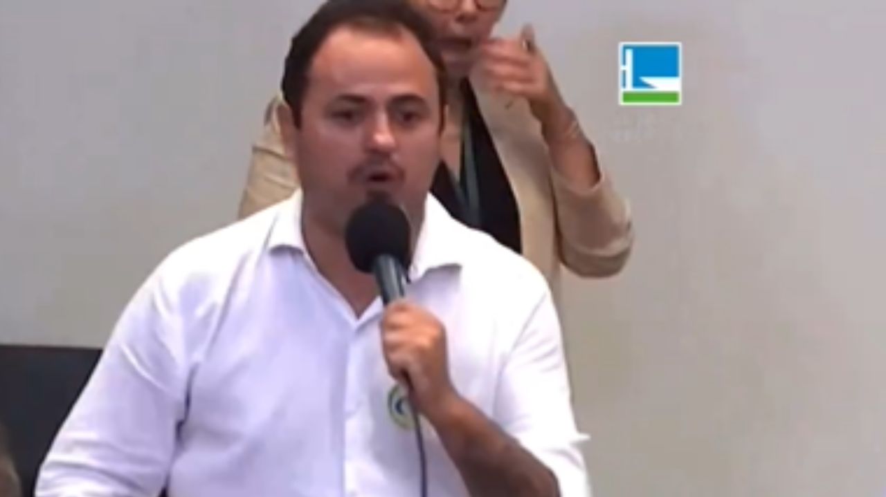 Glauber Braga falando em microfone com camisa social branca