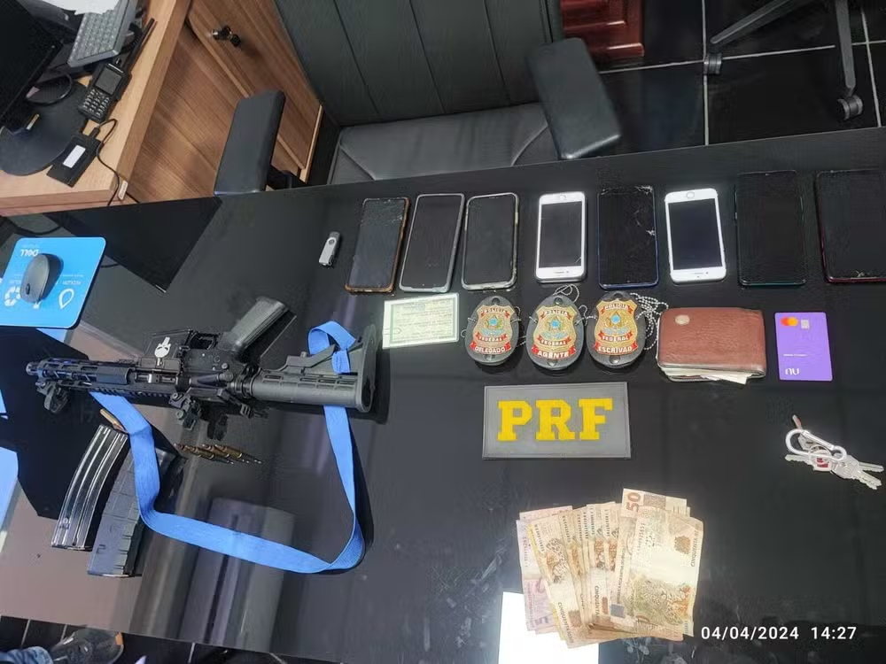 Celulares, dinheiro e arma encontrados com fugitivos de Mossoró em cima de mesa preta da PRF