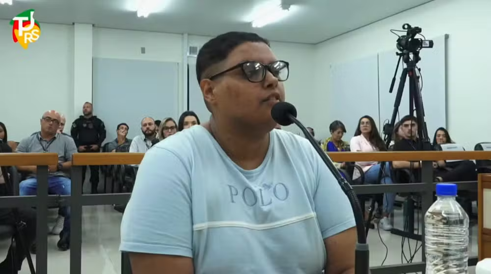 Bruna Nathiele Porto da Rosa de camiseta azul clara, de óculos, falando em microfone