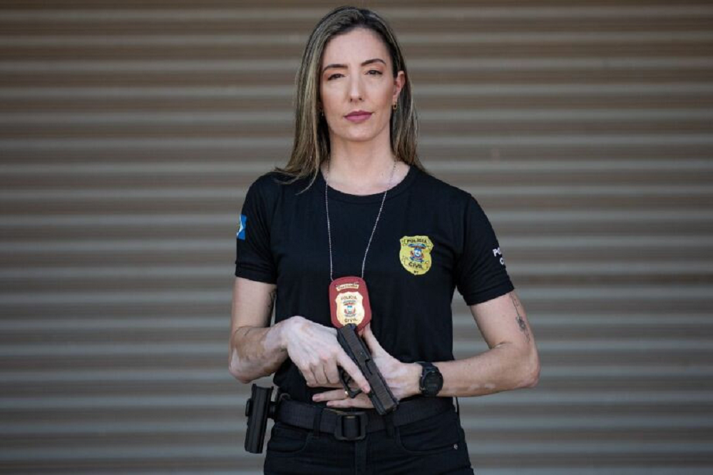 Juliana Chiquito Palhares com roupa preta e expressão séria, segurando arma