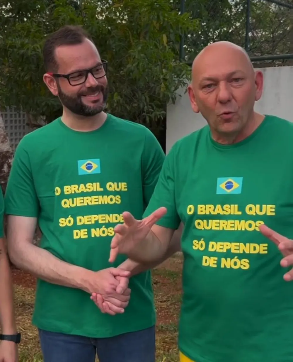 Jorge Seif e Luciano Hang de camisetas verdes, lado a lado, o primeiro sorrindo e o segundo falando