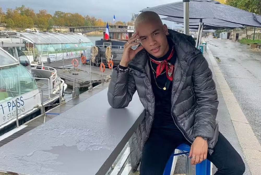 Yuri Henrique Gabriel Santos de Castro posando sério, de roupa de frio, perto de barcos