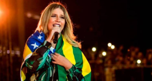 Marília Mendonça cantando enrolada em bandeira do Brasil