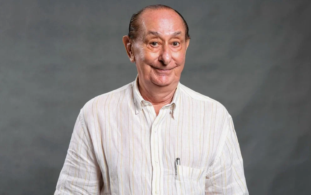 José Santa Cruz sorrindo timidamente para foto, com camisa social clara