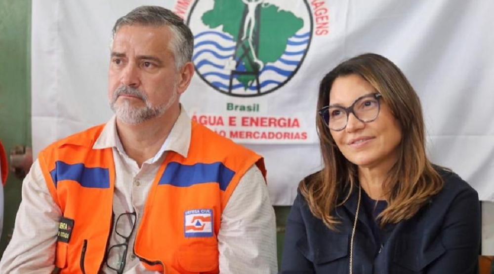 Paulo Pimenta e Janja sentados lado a lado, ambos sem olhar para a câmera