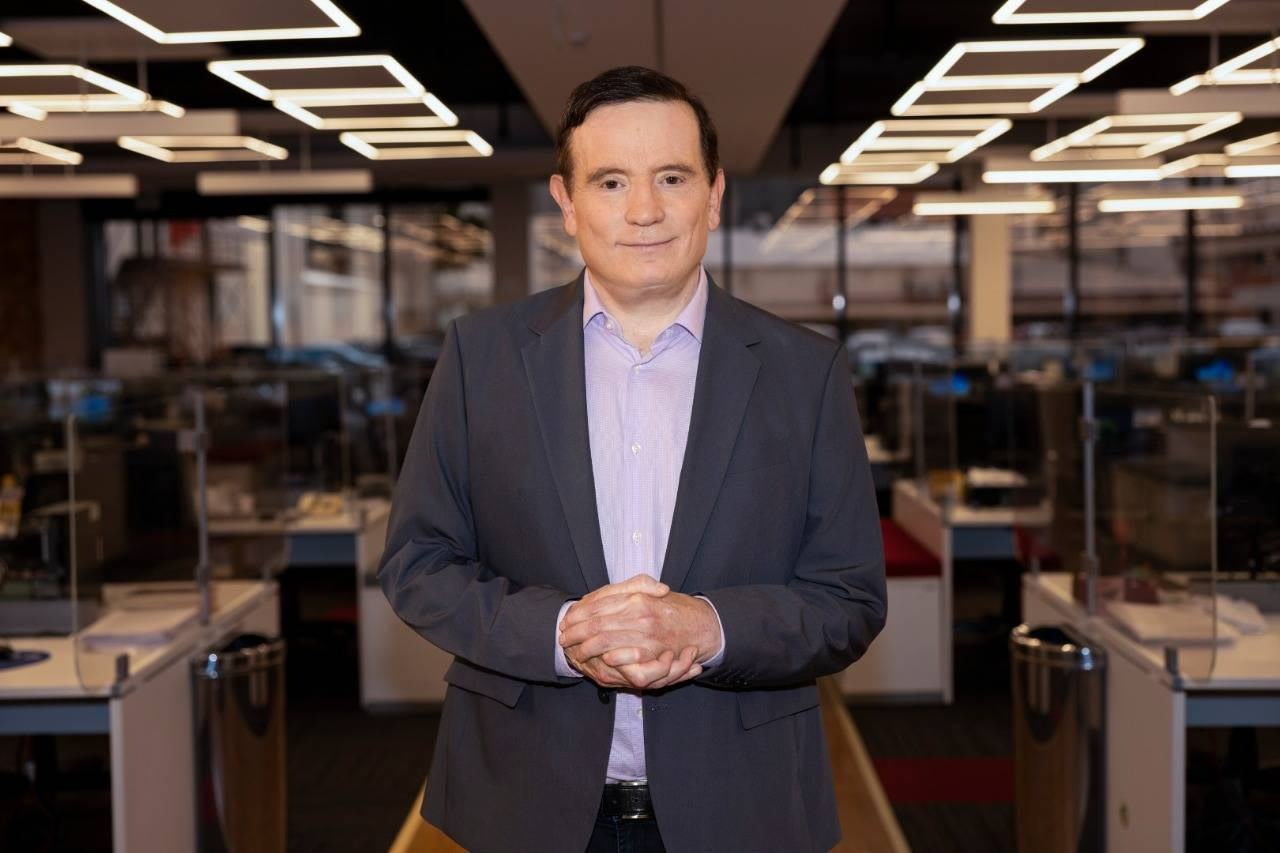 Roberto Cabrini posando para foto em redação, com expressão séria