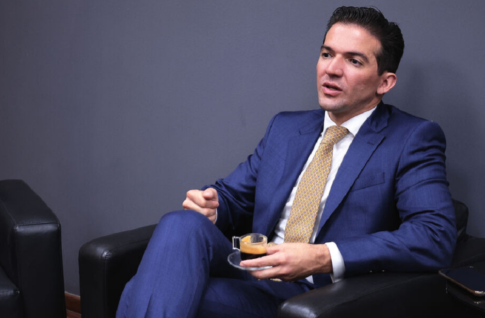 Rubinho Nunes falando, sentado em poltrona preta, com expressão séria
