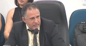 Vereador Hermes Costa falando e gesticulando, de roupa social, olhando para o lado