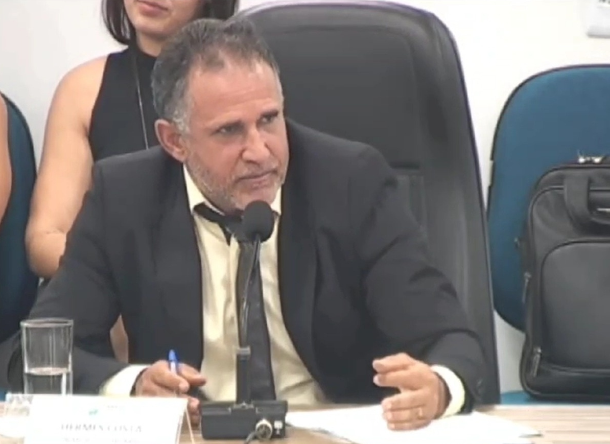 Vereador Hermes Costa falando e gesticulando, de roupa social, olhando para o lado