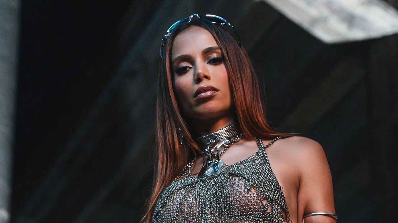Anitta com roupa prateada e óculos escuros na cabeça, fazendo carão para foto