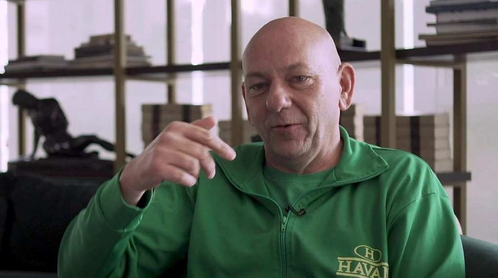 Luciano Hang com moletom verde da Havan, falando e gesticulando sem olhar para a câmera