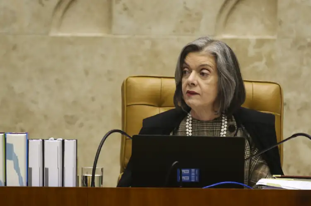 Ministra Cármen Lúcia com expressão séria, olhando para o lado, no canto direito de foto