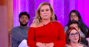 Christina Rocha de blusa de frio vermelha e cabelo solto, com expressão séria