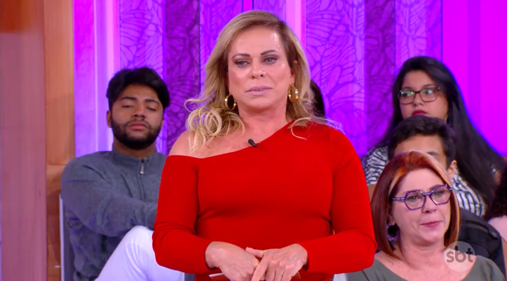 Christina Rocha de blusa de frio vermelha e cabelo solto, com expressão séria