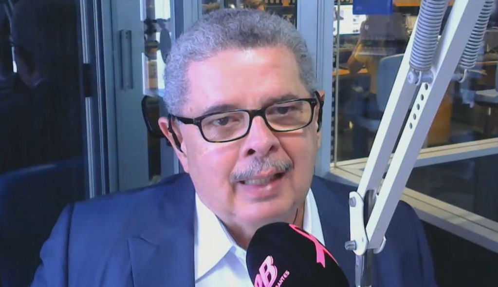 Cláudio Humberto falando em microfone, de óculos