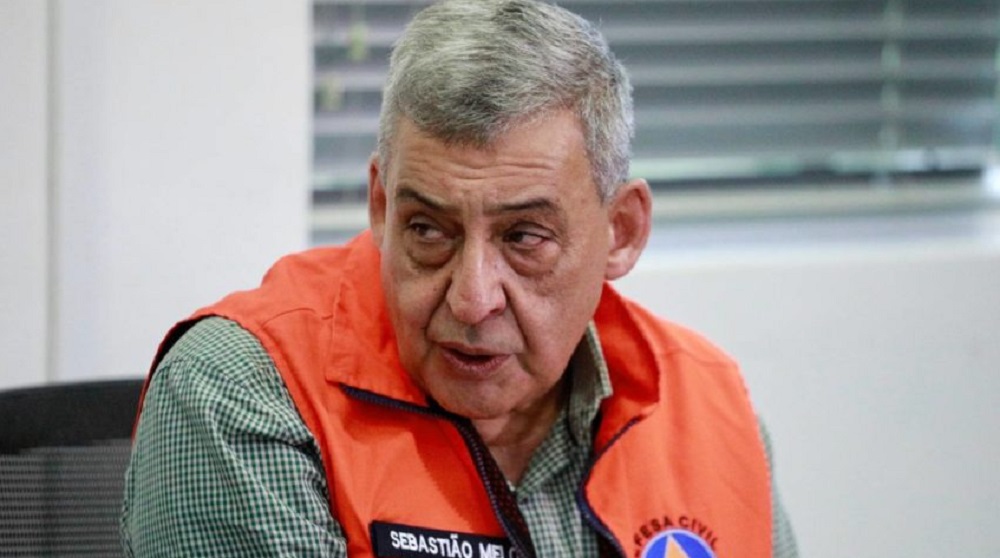 Sebastião Melo de colete laranja, falando e olhando para o lado com expressão séria
