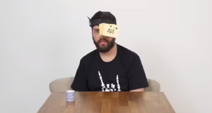 Diogo Defante de camiseta preta e olho esquerdo coberto por post-its, com expressão séria
