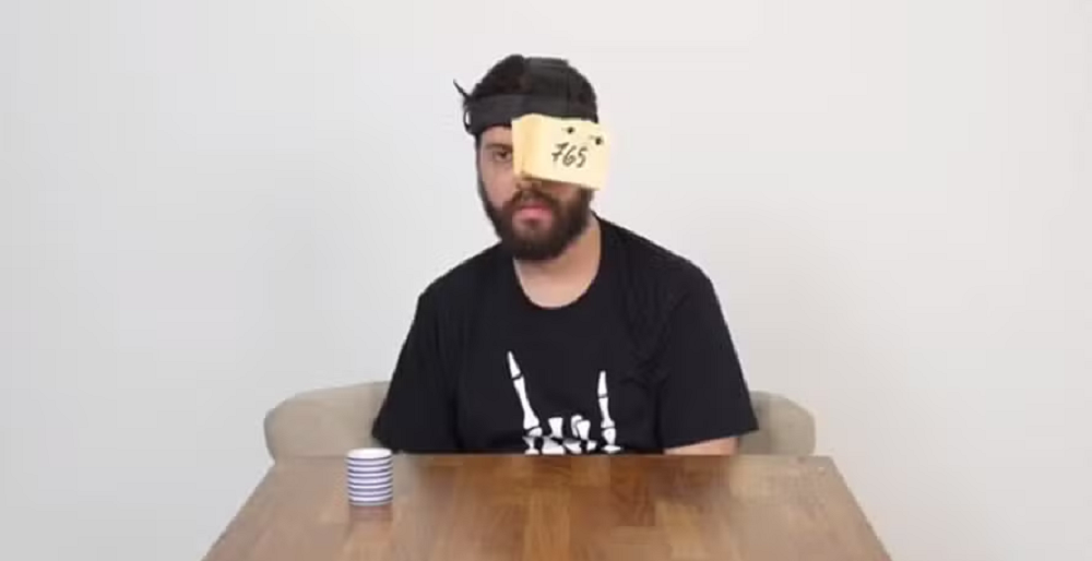 Diogo Defante de camiseta preta e olho esquerdo coberto por post-its, com expressão séria