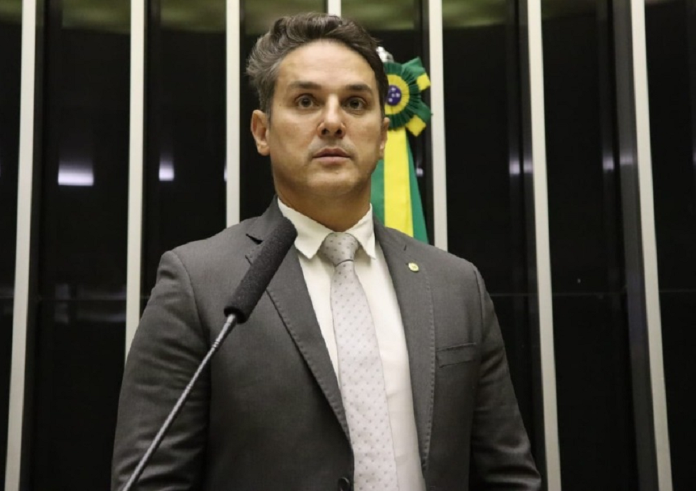 Coronel Zucco em pé, de roupa social, sério, olhando pra frente