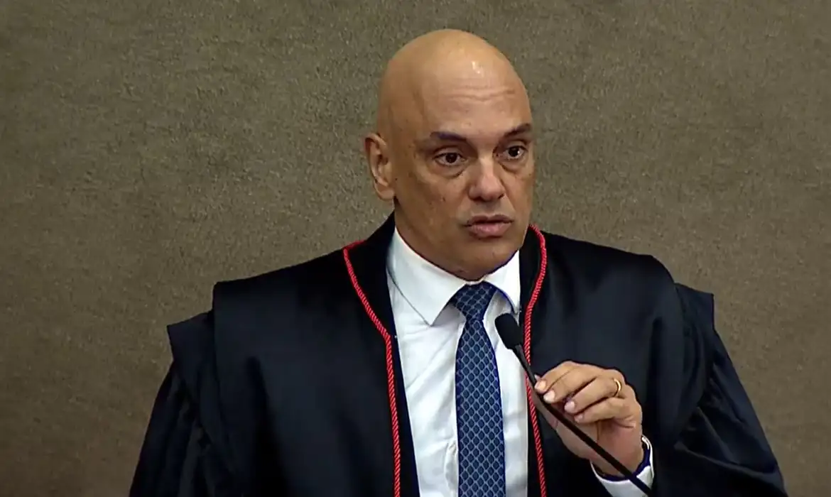 Alexandre de Moraes falando em microfone com expressão séria