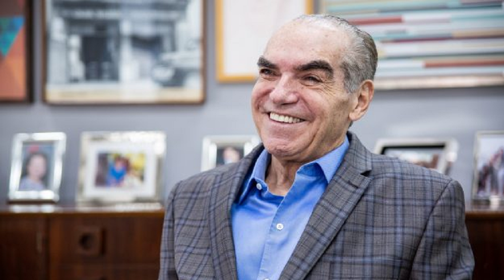 Michal Klein rindo sem olhar para a câmera, de roupa social