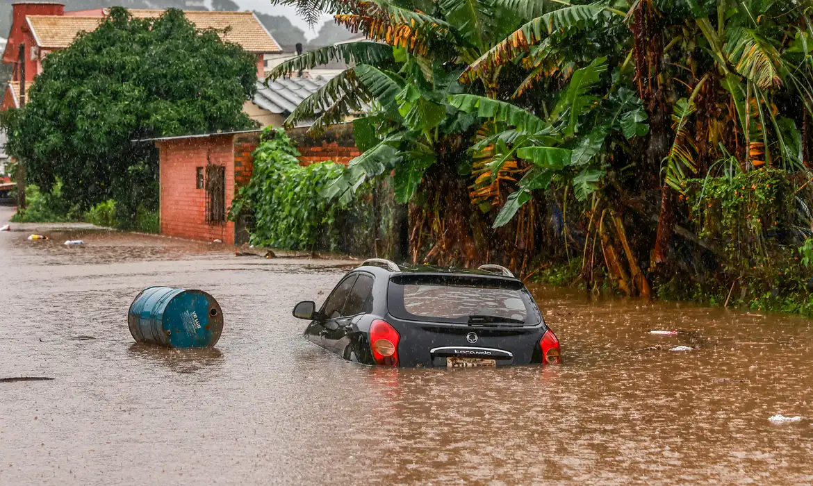 Rua alagada em cidade do Rio Grande do Sul, com carro preto quase todo debaixo d'água