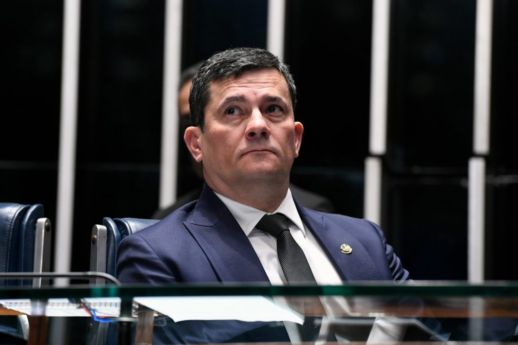 Sergio Moro de terno e gravata, olhando pra cima com expressão séria