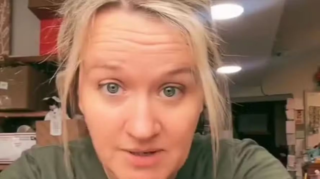 K de cabelo preso e camiseta verde, falando para a câmera