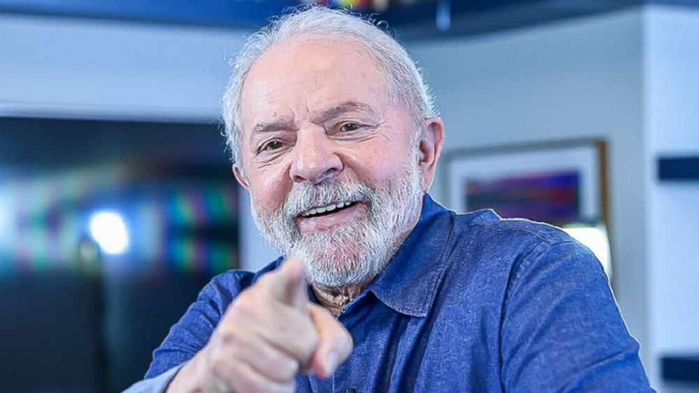 Lula de camisa jeans, sorrindo e apontando para a câmera