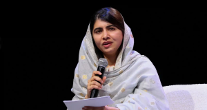 Malala Yousafzai falando em microfone e segurando papel