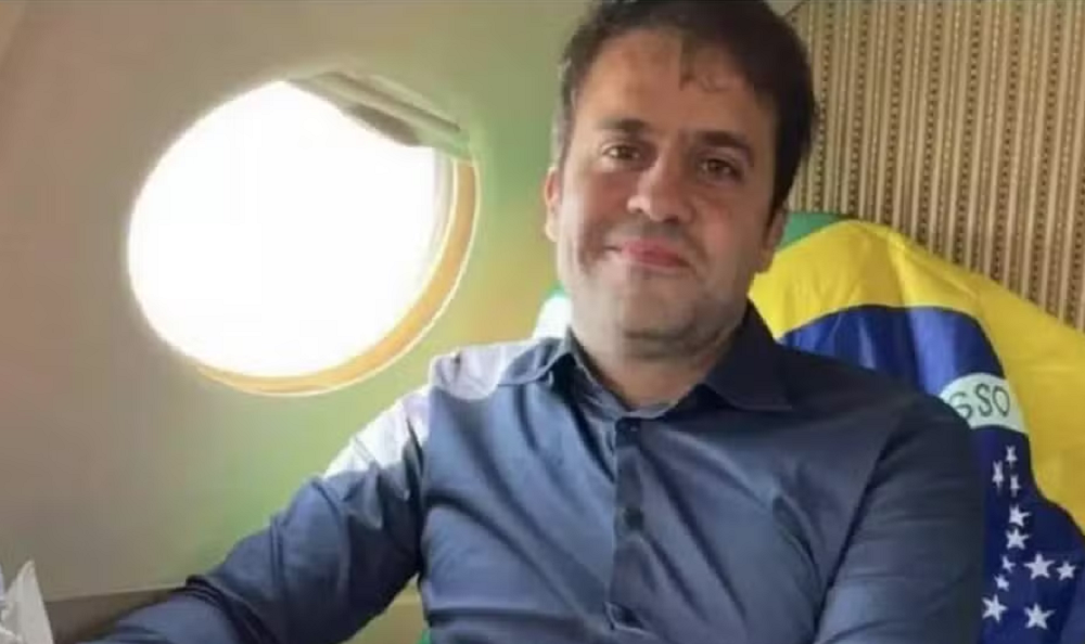 Pablo Marçal perto de janela de avião com bandeira do Brasil ao fundo, sem sorrir