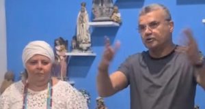 Mãe de Santo ao lado de pastor, que está de camisa cinza, falando e gesticulando