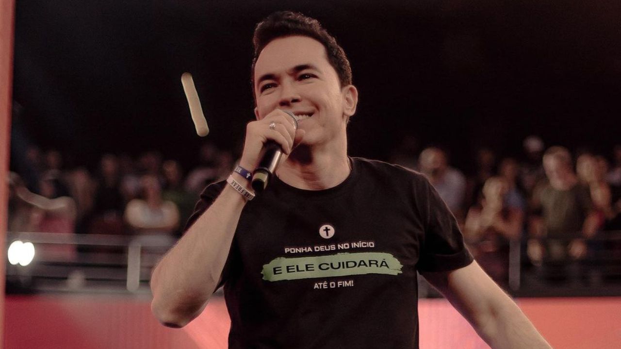Pastor Lucinho Barreto de camiseta preta falando em microfone e sorrindo