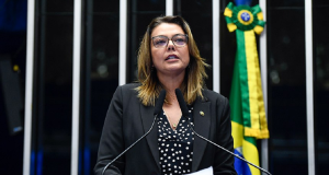 Senadora Leila Barros (PDT-DF) falando em microfone, de roupa preta, em pé