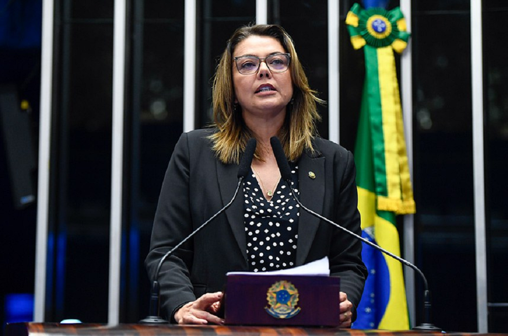 Senadora Leila Barros (PDT-DF) falando em microfone, de roupa preta, em pé