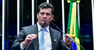 Sergio Moro de terno e gravata, falando em microfones com expressão séria