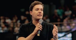 André Valadão de roupa preta, falando em microfone sem olhar para a câmera, gesticulando