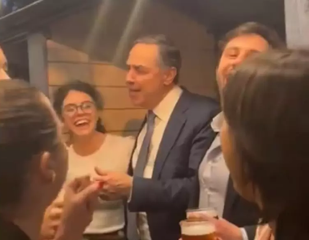 Luís Roberto Barroso rodeado de jovens, cantando