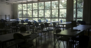 Sala de aula vazia, só com mesas e cadeiras, de dia