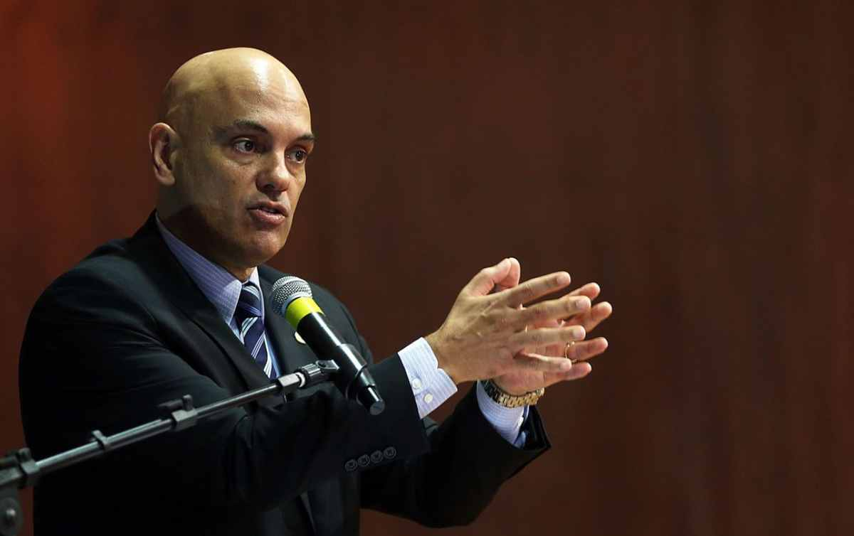 Alexandre de Moraes no canto esquerdo da foto, falando em microfone e gesticulando