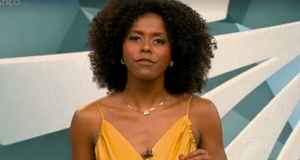 Maju Coutinho de roupa amarela, falando e gesticulando para a câmera no cenário do Fantástico