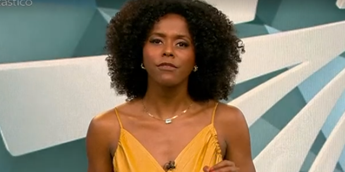 Maju Coutinho de roupa amarela, falando e gesticulando para a câmera no cenário do Fantástico