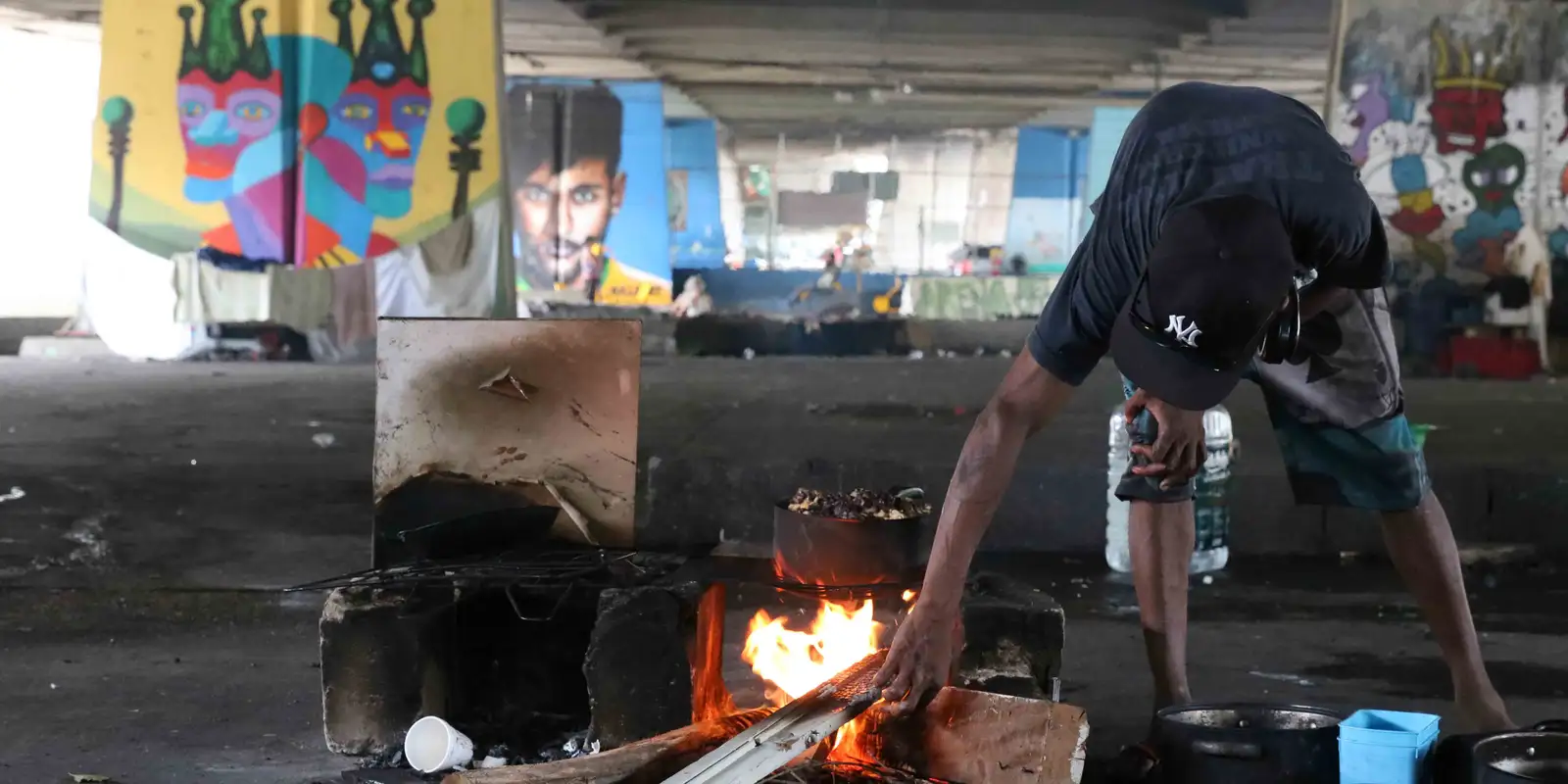 Homem em situação de rua fazendo fogueira