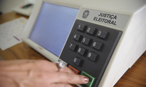 Mão apertando urna eletrônica