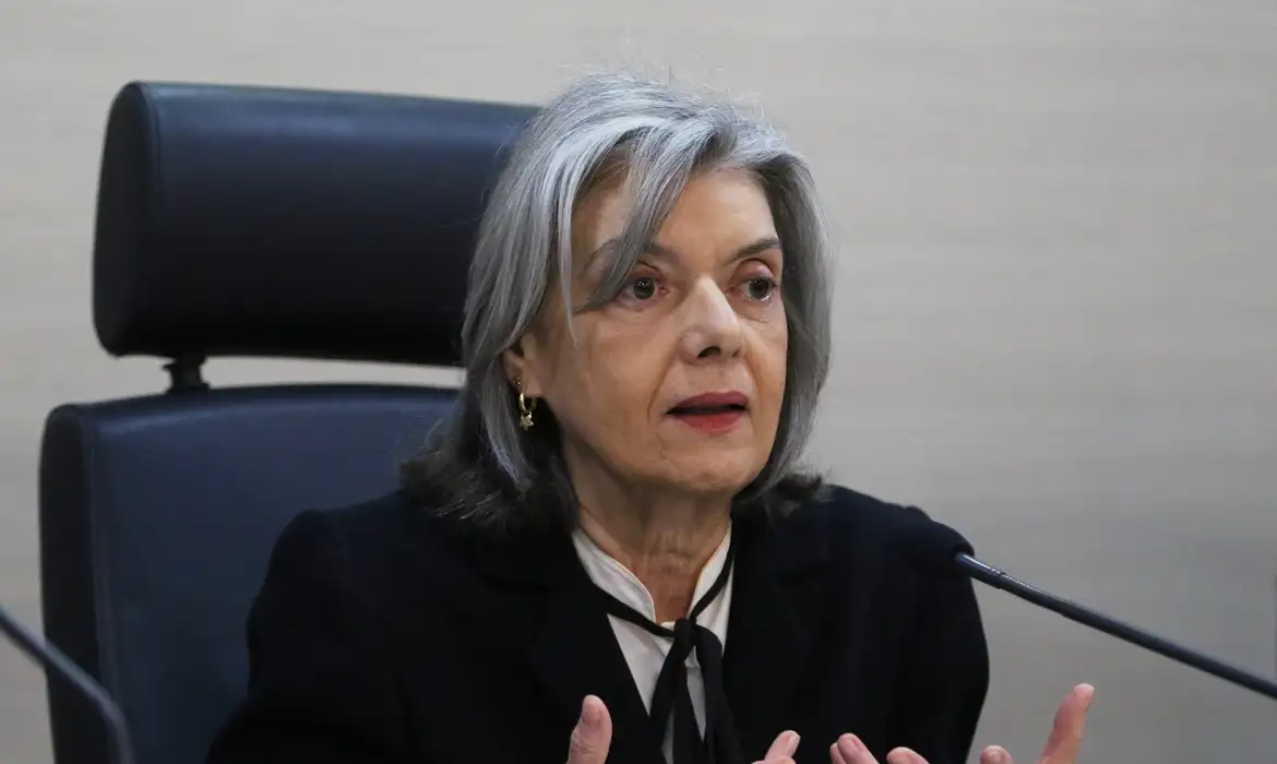 Cármen Lúcia de roupa preta e branca, falando com expressão séria e gesticulando